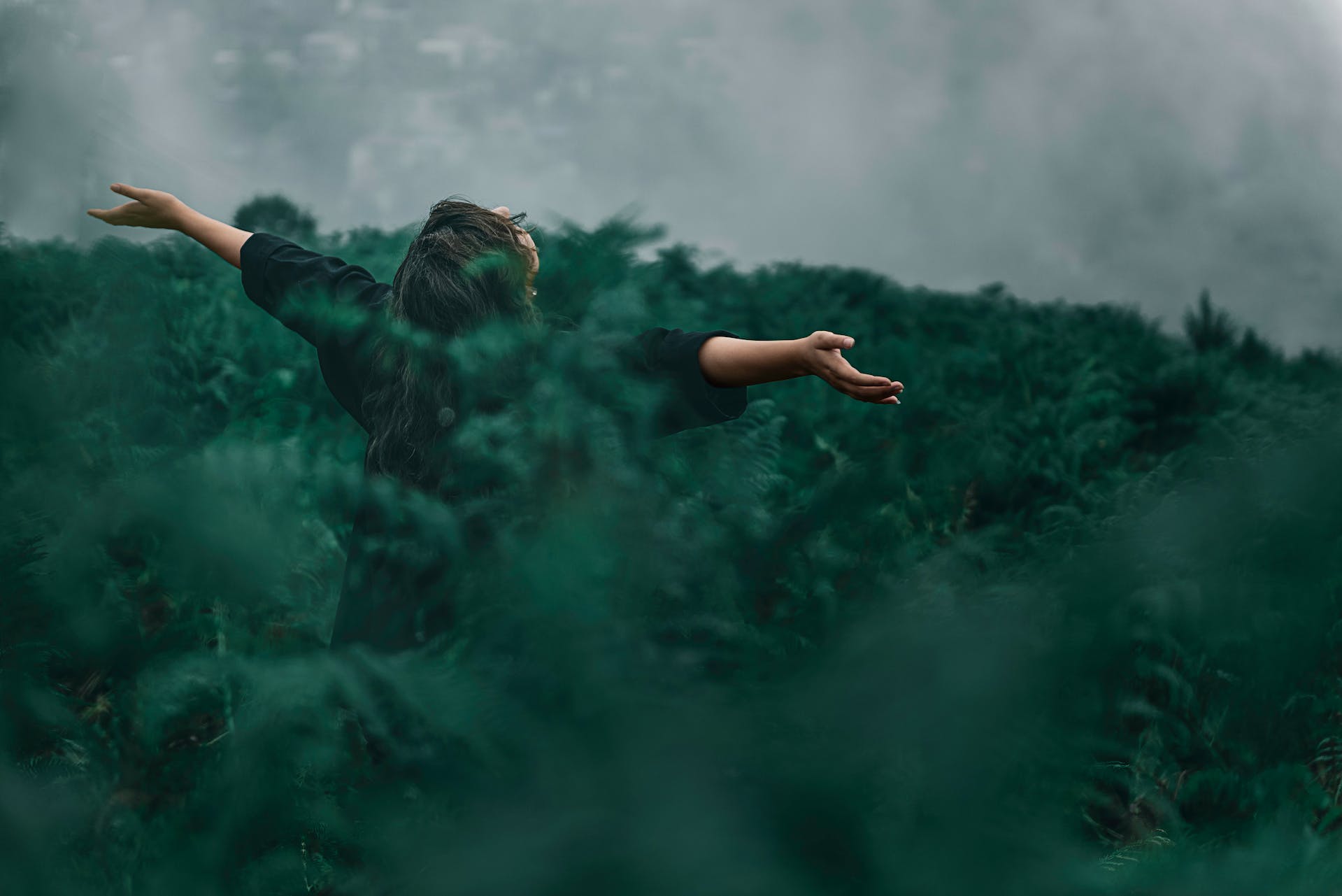 lady surrounded in a cloud of green smoke facing away with her hands spread out